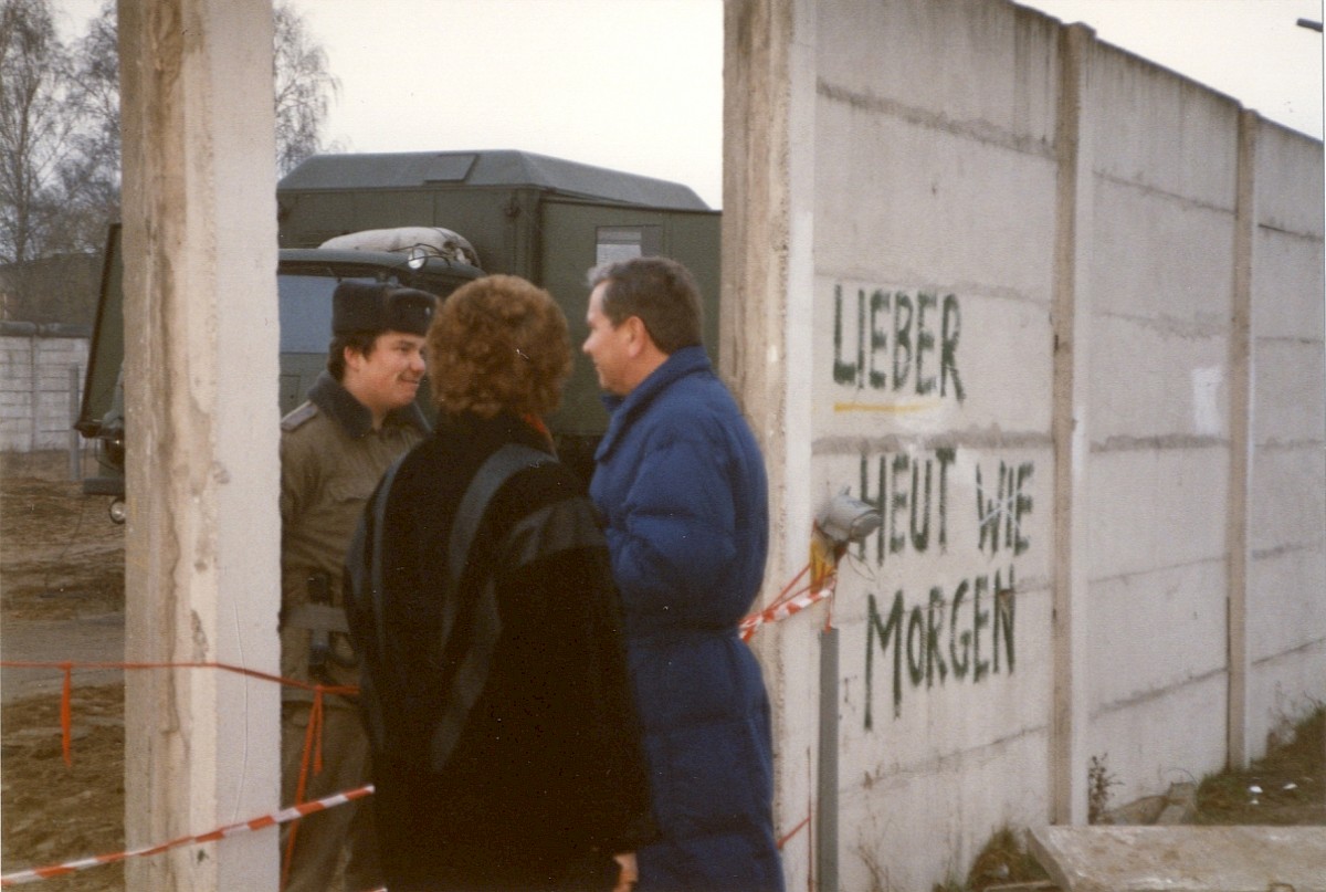 Berlin, 14. Januar 1990 – Paar unterhält sich durch eine Mauerlücke in der Hinterlandmauer mit einem Grenzsoldaten (Fotograf: Monika Waack)
