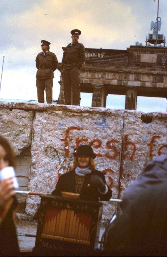 Berlin, 1990 – Leierkastenspielerin an der Panzermauer am Brandenburger Tor (Fotograf: )