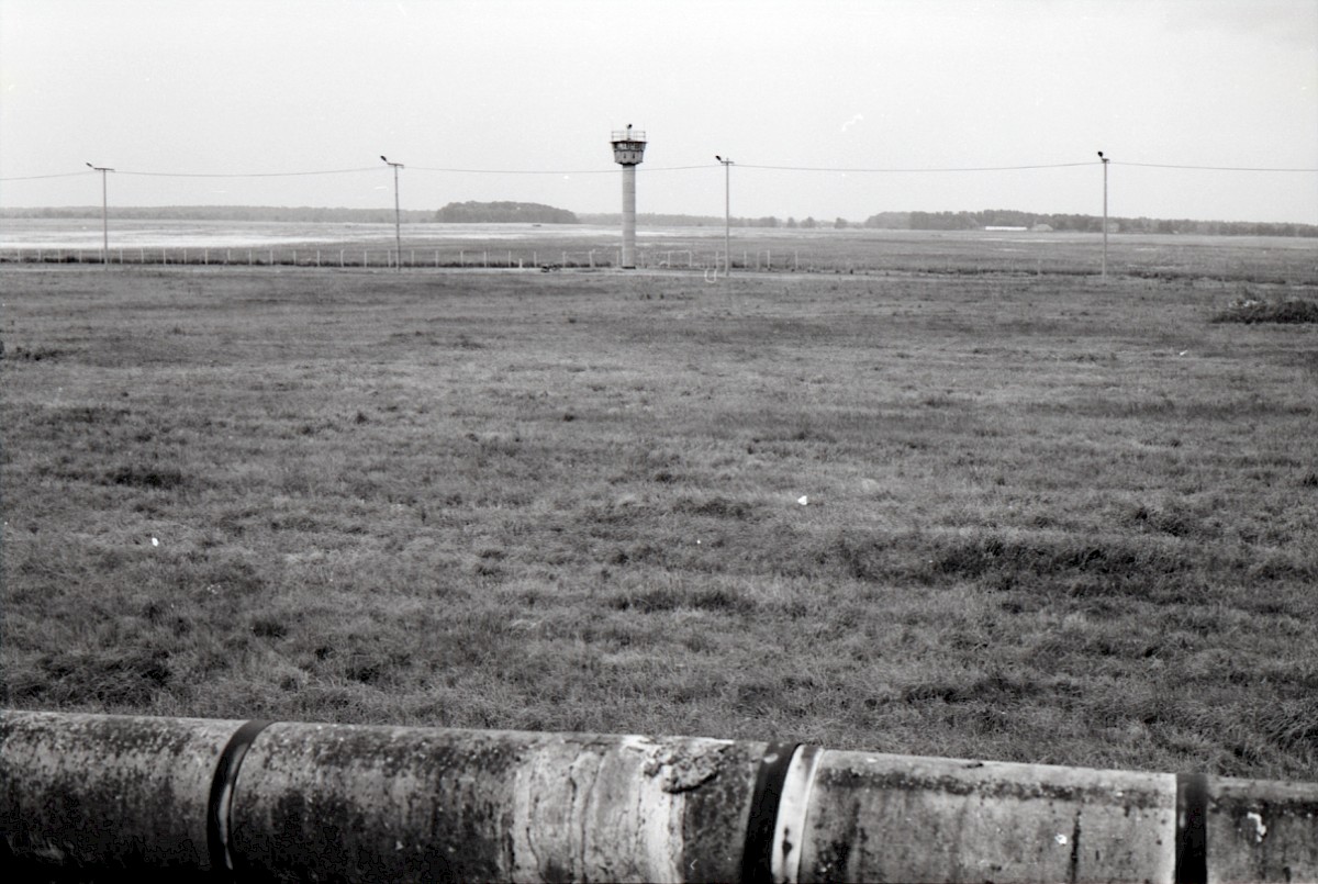Berlin, 1984 – Grenzstreifen am Außenring mit Rohrauflage und Wachturm am Tilkeroder Weg (Fotograf: Albrecht Roos)