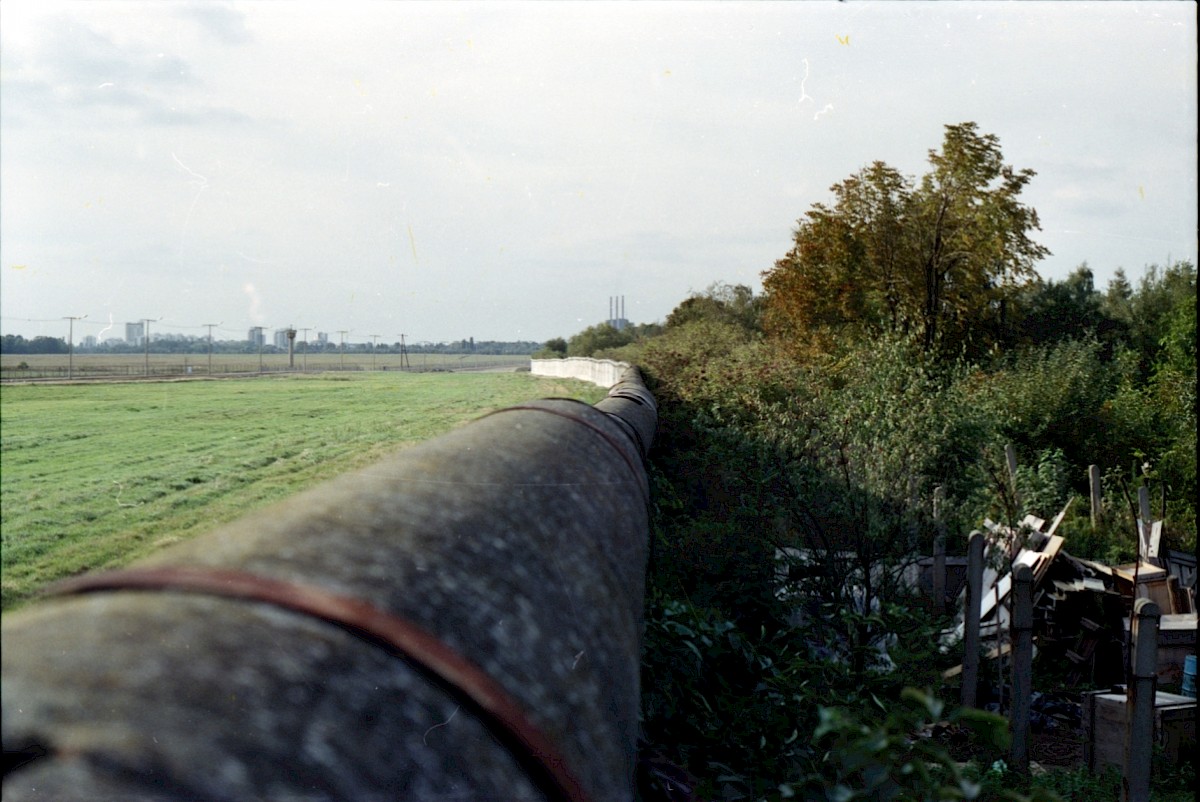 Berlin, 1988 – Rohrauflage und Kleingarten am Grenzstreifen in Marienfelde (Fotograf: Albrecht Roos)