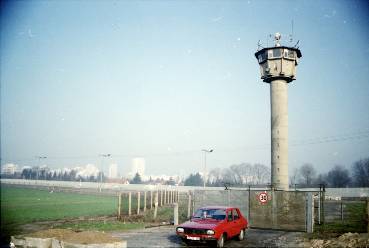 Berlin, ca. 1990 – Ostansicht des geöffneten Grenzstreifens mit verlassenem Wachturm und Zufahrtstor an der Marienfelder Allee (Fotograf: Albrecht Roos)