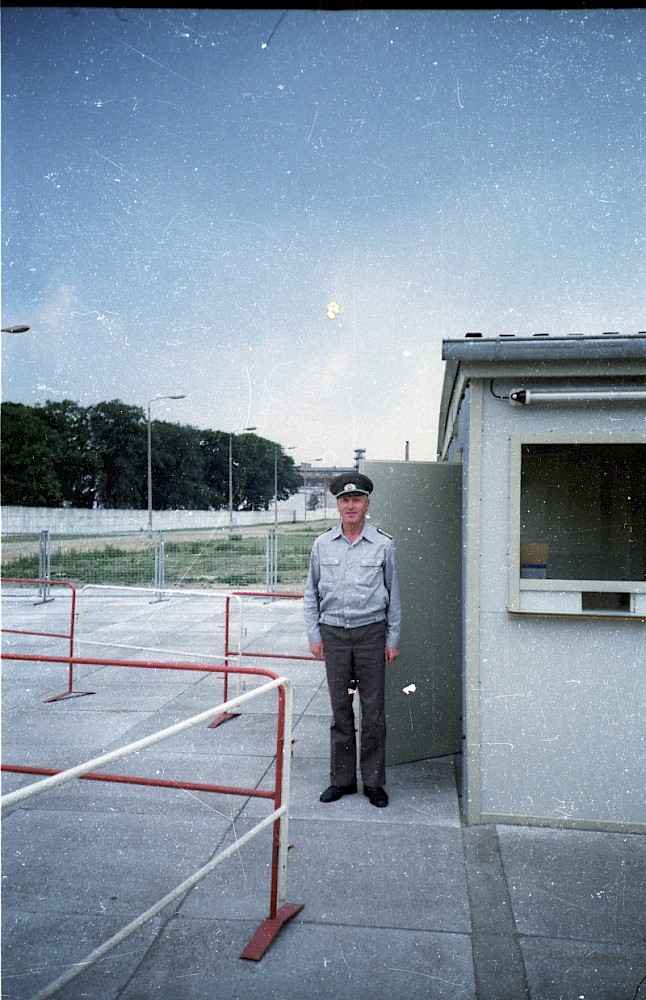 Berlin, 1990 – Ein PKE-Angehöriger neben einem Kontrollhaus am Grenzübergang Puschkinallee (Fotograf: Hans-Jürgen Klette)