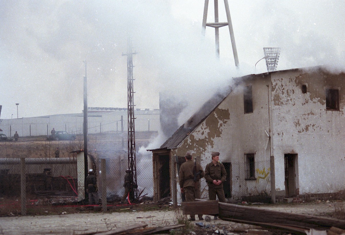 Berlin, 5. März 1989 – Grenzsoldaten bewachen den Feuerwehreinsatz an der Grenzmauer in der Schwedter Straße (Fotograf: Detlef Machmüller)