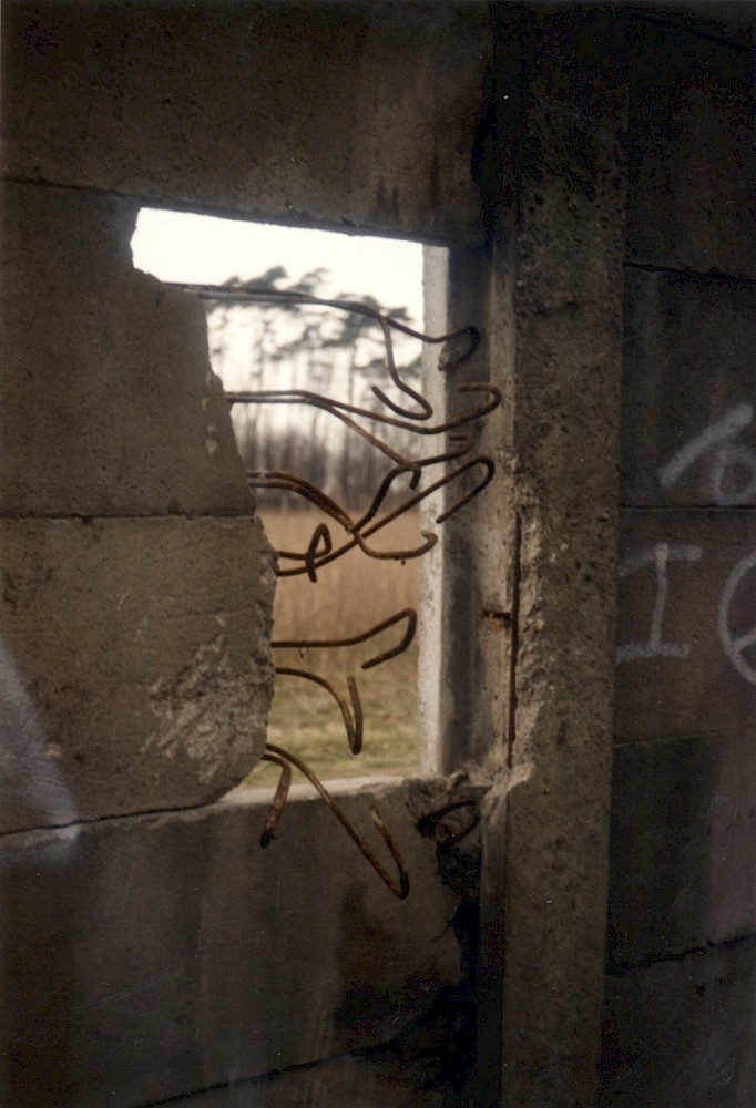 Berlin, Februar/März 1990 – Metallstreben ragen aus einer Mauerlücke in der Betonplattenmauer hervor (Fotograf: Monika Waack)