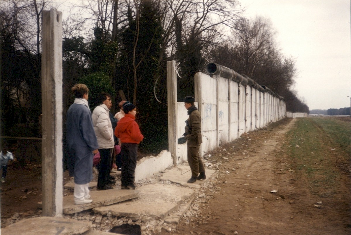 Berlin, Februar/März 1990 – Unterhaltung von Personengruppe und Grenzsoldat an der Betonplattenmauer in Lichtenrade (Fotograf: Monika Waack)