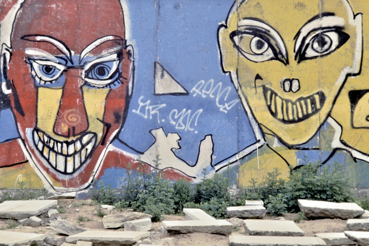 Berlin, ca. 1986 – Zwei gemalte, etwas fies grinsende Köpfe an der Grenzmauer 75 (Fotograf: Detlef Gallinge)