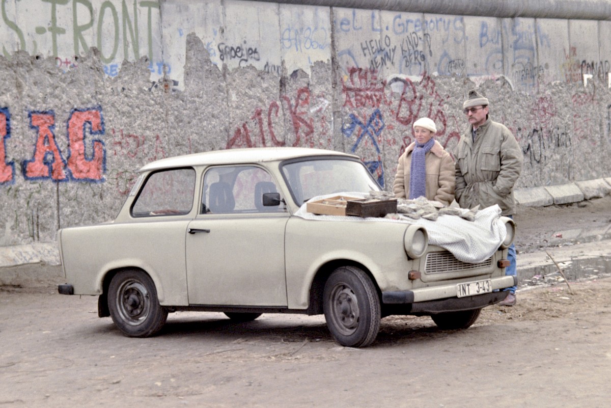 Berlin, 1990 – Mauerstück-Händler verkaufen Mauerstücke von der Motorhaube ihres Trabants (Fotograf: Detlef Gallinge)
