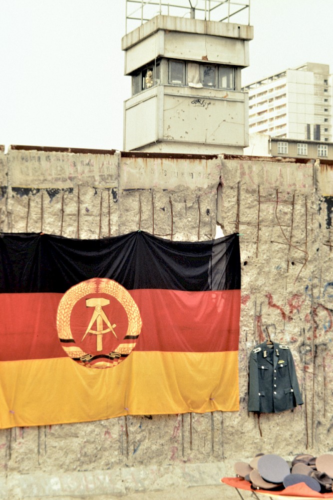 Berlin, 1990 – Verkauf verschiedener Uniformstücke und eine DDR-Fahne in der Markgrafenstraße (Fotograf: Detlef Gallinge)