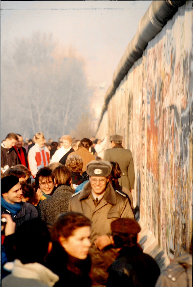Berlin, November 1989 – Menschenmenge mit Grenzsoldat drängt sich entlang der Grenzmauer 75 (Fotograf: Detlef Gallinge)
