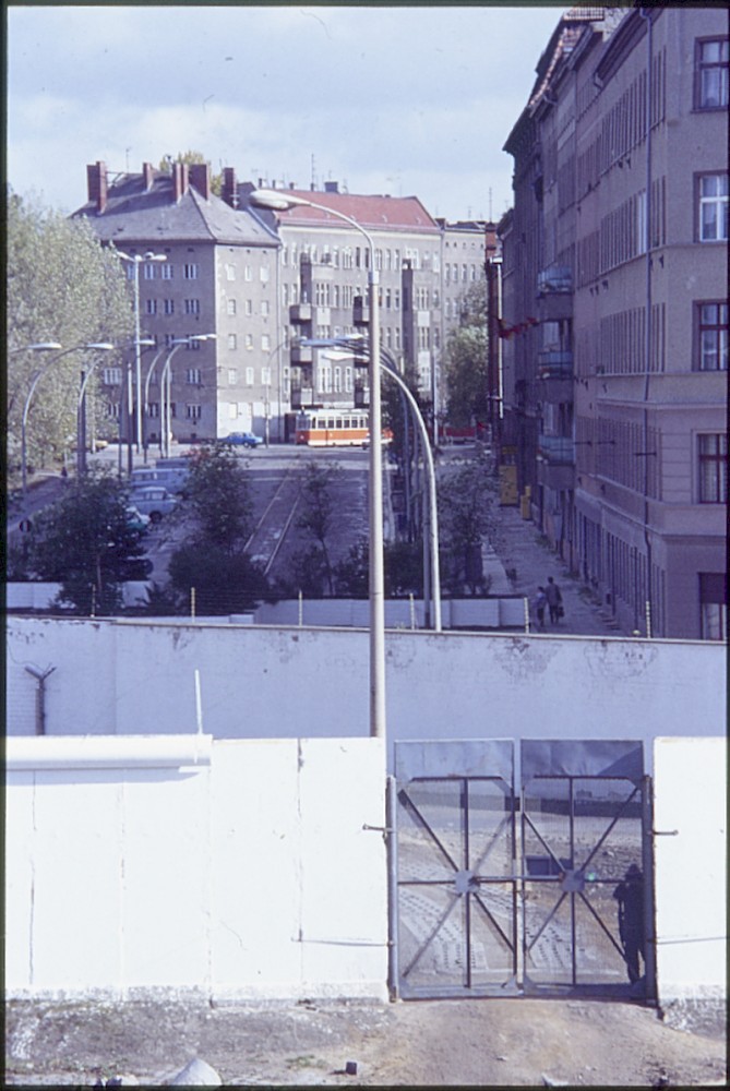 Berlin, 7. Oktober 1989 – Grenzoldat hinter dem Zufahrtstor an der Kreuzung Bernauer Straße/Eberswalder Straße (Fotograf: Lothar Kruse)