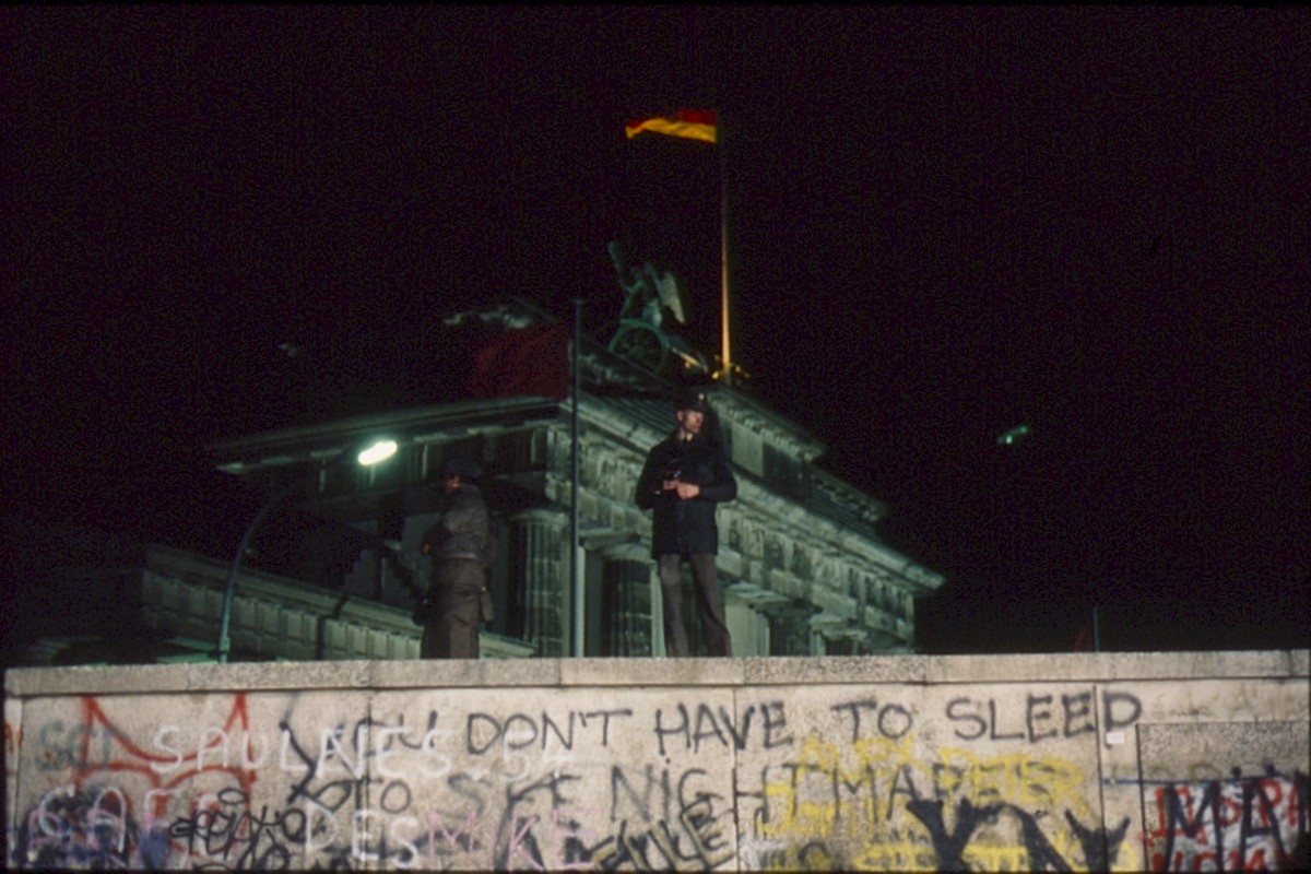 Berlin, 22. Dezember 1989 – Grenzsoldaten stehen auf der Panzermauer am Brandenburger Tor bei Nacht (Fotograf: Lothar Kruse)