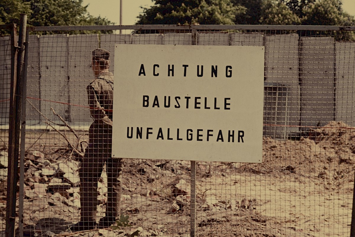 Berlin, Juni 1980 – Warnschild beim Aufbau Grenzmauer 75 und Grenzsoldat an der Bernauer Straße/Ackerstraße (Fotograf: Conrad Bicker)