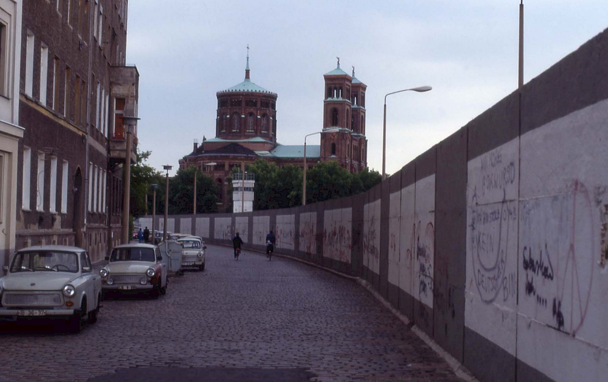 Berlin, 1990 – Hinterlandmauer mit Graffiti am Engeldamm und Sankt Thomas-Kirche (Fotograf: )