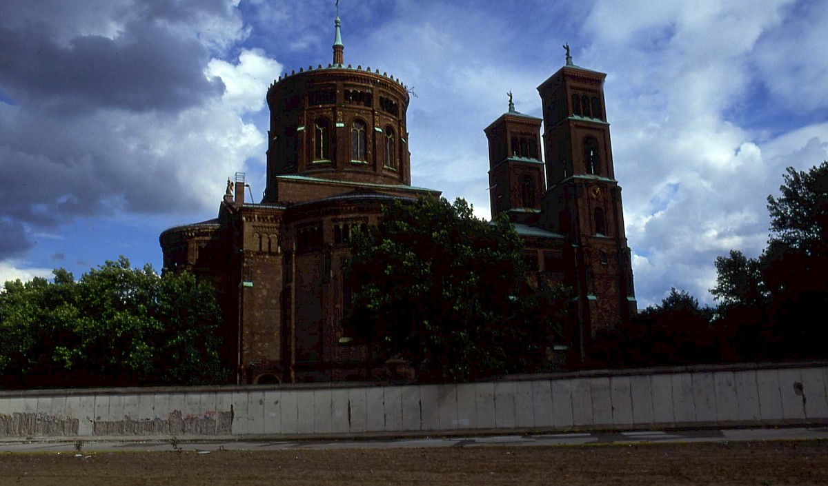 Berlin, 1990 – Grenzmauer vor der Sankt Thomas-Kirche am Bethaniendamm nach Mauerfall (Fotograf: )